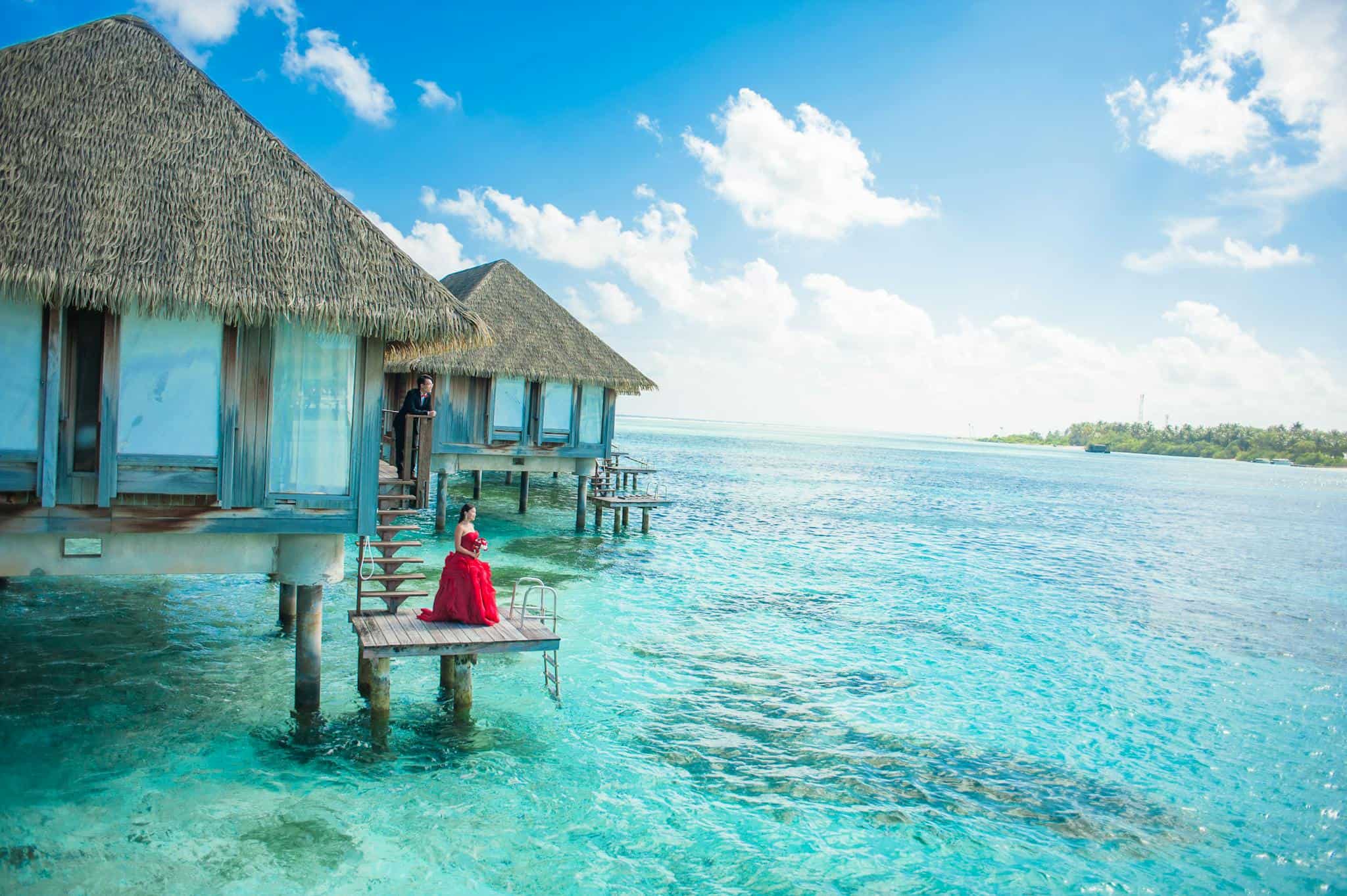 Idyllic Maldives overwater bungalows with turquoise lagoon and a couple enjoying paradise.